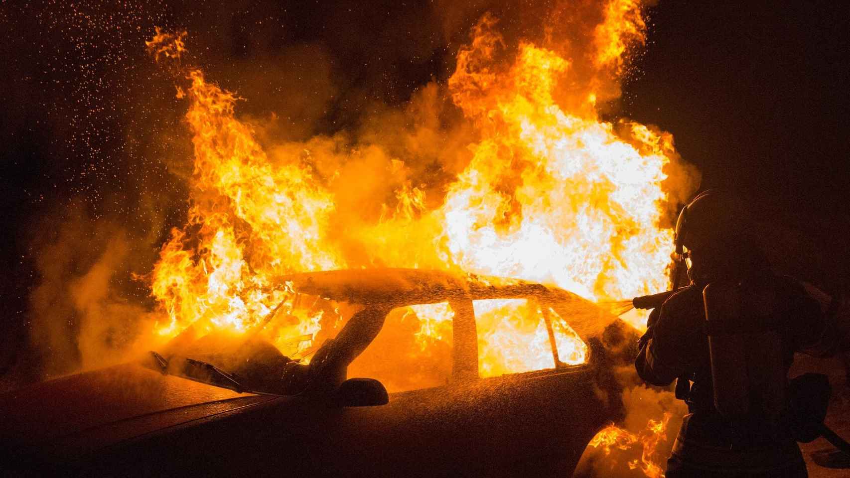 Un bombero apaga un coche incendiado / CG