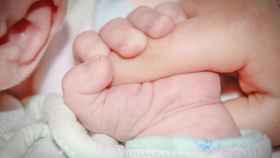Un bebé coge el dedo a su madre / CG