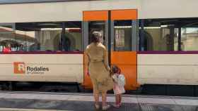 Una mujer y una niña frente a un tren de Rodalies Renfe / EP