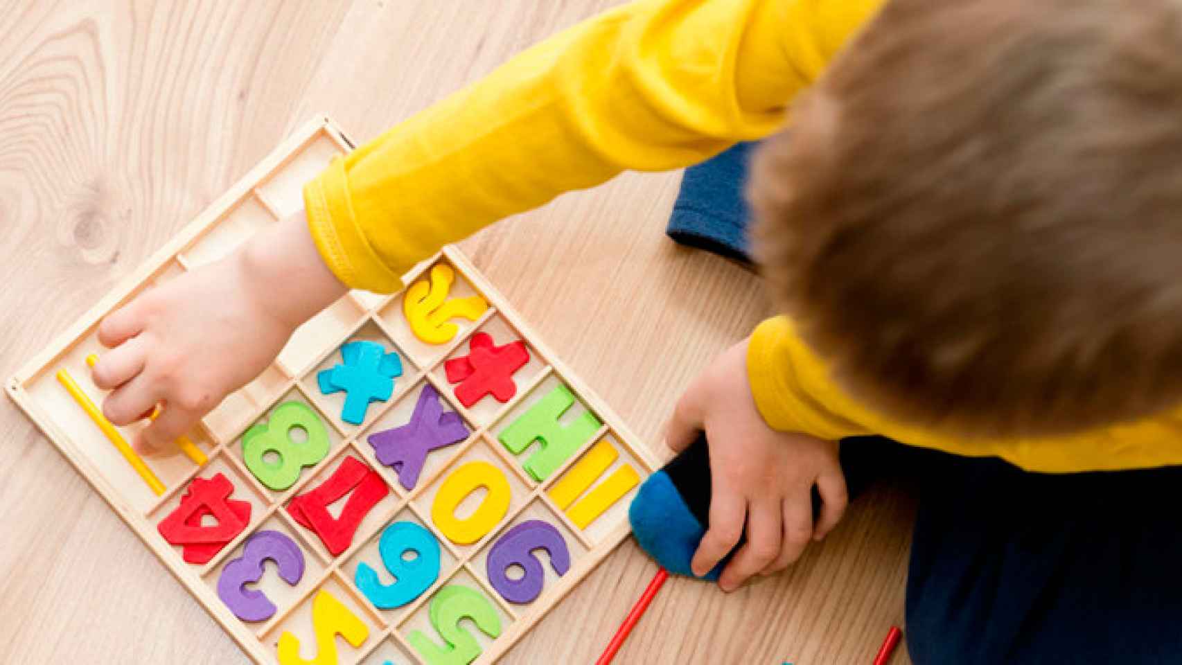 Un niño jugando en la escuela con letras y números / CG