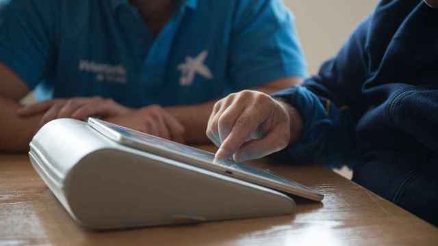Voluntaria de La Caixa enseña a una persona el uso de tablets para comunicarse con sus familiares /LA CAIXA