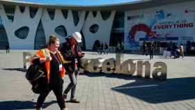 Dos congresistas pasean por la puerta de entrada al MWC en el recinto de la Fira de Barcelona / EFE