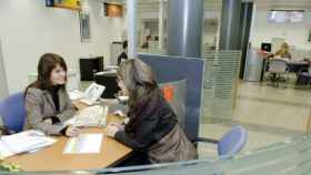 La empleada de un banco ayuda a una clienta en una de sus oficinas. / CG