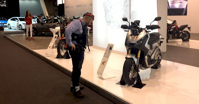 Un agente de seguridad mira una de las motos expuestas en el salón del automóvil de Barcelona en los primeros días del evento / CG