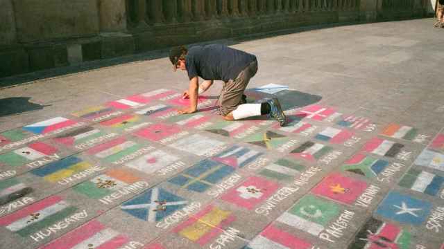 Hombre dibujando banderas en el suelo / PEXELS