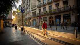Una mujer circula en bici por el Raval de Barcelona con muchos comercios cerrados / EP