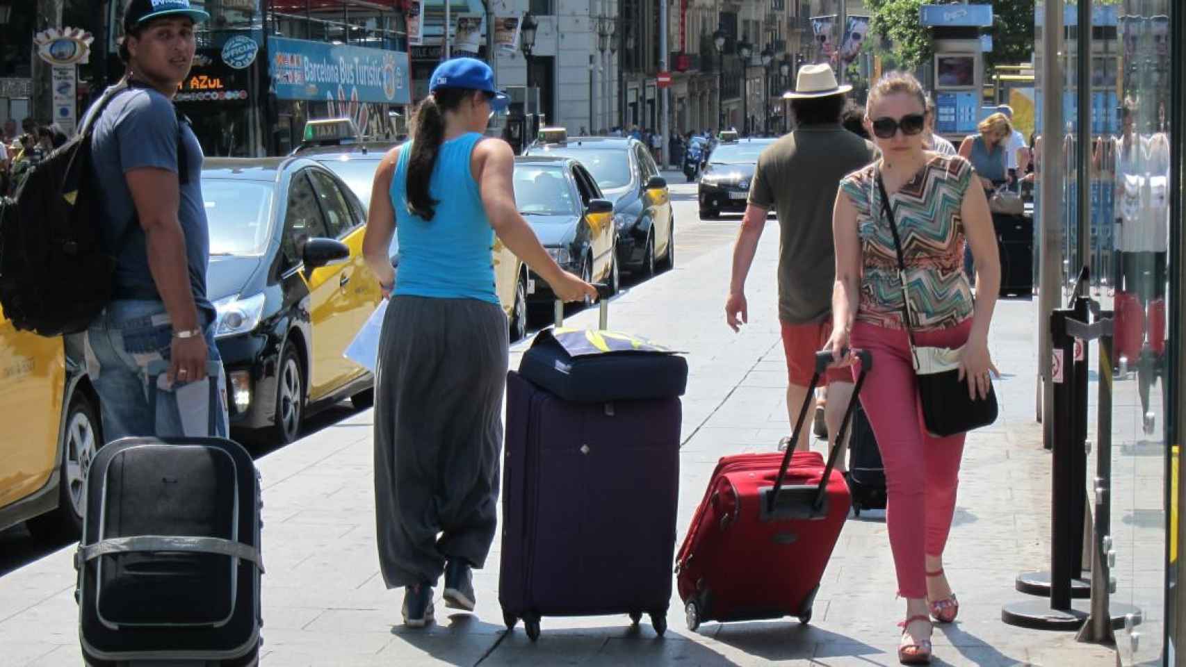 Varios turistas cargan sus maletas en una calle de Barcelona, cuya llegada conllevará una recuperación del empleo en el sector turístico / EP