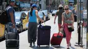 Varios turistas cargan sus maletas en una calle de Barcelona, cuya llegada conllevará una recuperación del empleo en el sector turístico / EP