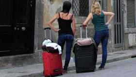 Dos turistas esperan con sus maletas con un piso turístico en Barcelona / GB