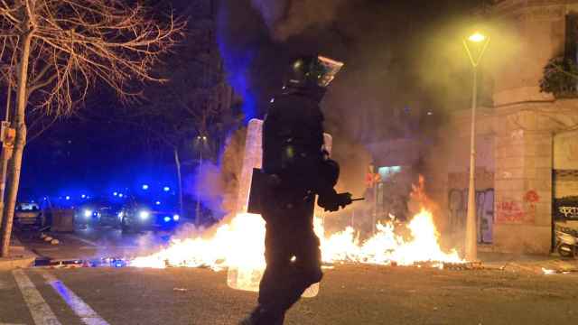 Un agente de la BRIMO (Mossos) ante una barricada en llamas el tercer día de disturbios por Hasél / ELENA BURÉS