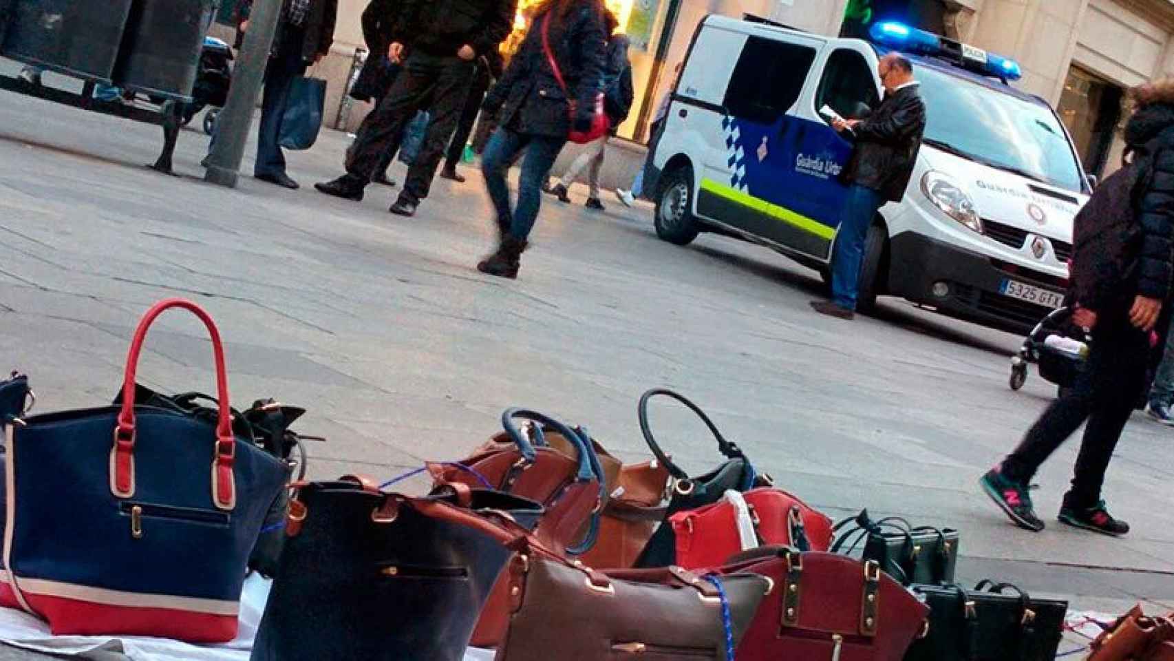 Una imagen de archivo de venta ambulante junto a un furgón de la Guardia Urbana de Barcelona