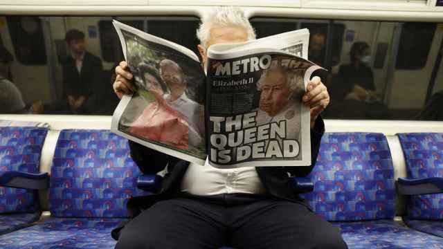 Un hombre lee un periódico con la noticia de la muerte de la reina Isabel II en portada, este viernes en Londres / EFE