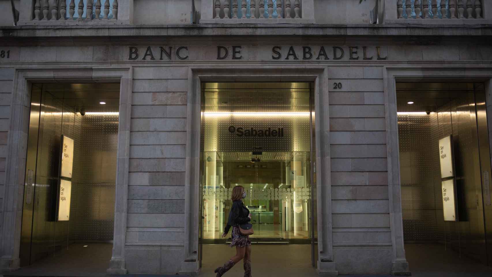 Una mujer pasa ante la sede histórica del Banco Sabadell / EP