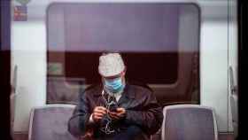 Un pasajero montado en un tren con una mascarilla quirúrgica contra el coronavirus / EFE