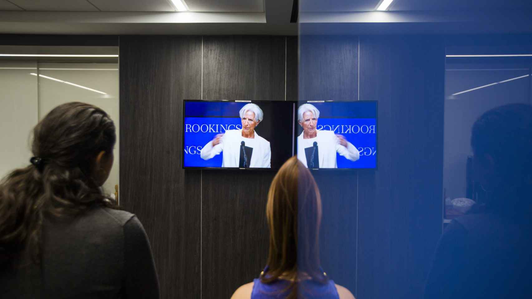 Dos de los asistentes al acto de anoche en Washington observan la intervención de Lagarde en una pantalla