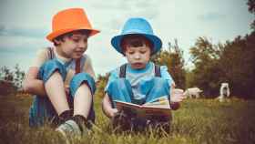 Dos niños leyendo libros en el campo / CG