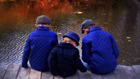 Tres hermanos sentados junto al agua / CG