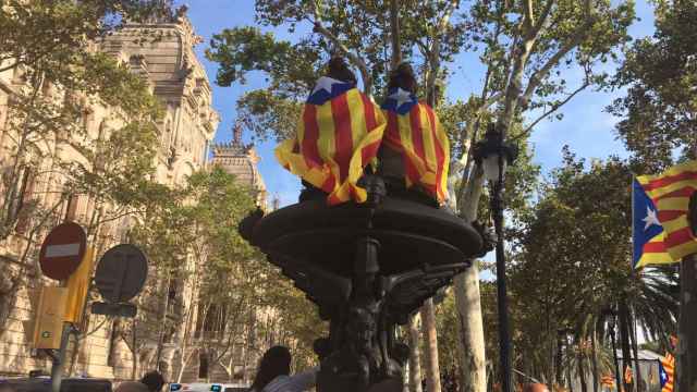 Dos jóvenes con banderas independentistas sentadas en una estatua del paseo Lluís Companys