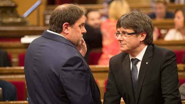 El presidente de la Generalitat Carles Puigdemont (d) y el vicepresidente económico, Oriol Junqueras, en el Pleno del Parlament / PARLAMENT