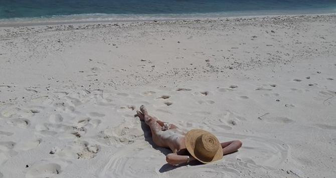Una bañista tomando el sol en una playa nudista / PXHERE