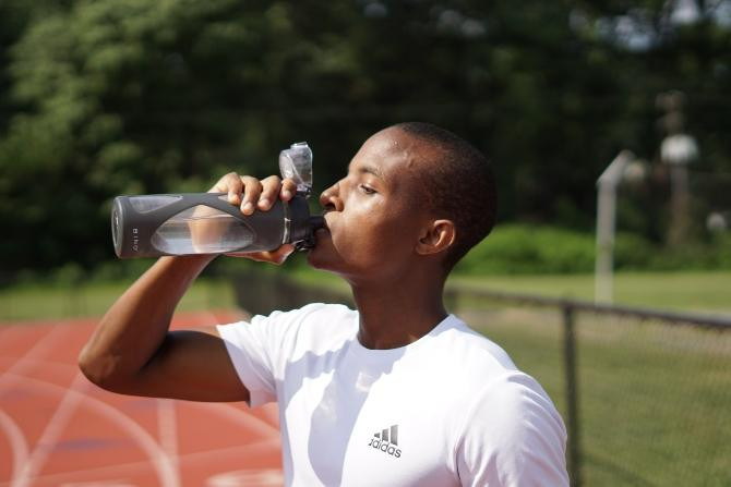 Un joven bebiendo agua, algo esencial si se practica running / Nigel Msipa en UNSPLASH