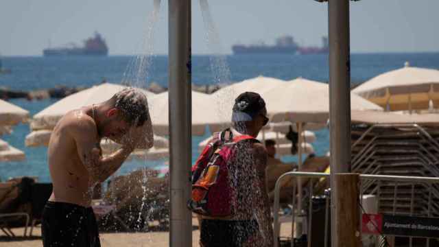 Varias personas se mojan en las duchas de la playa de la Barceloneta / EUROPA PRESS