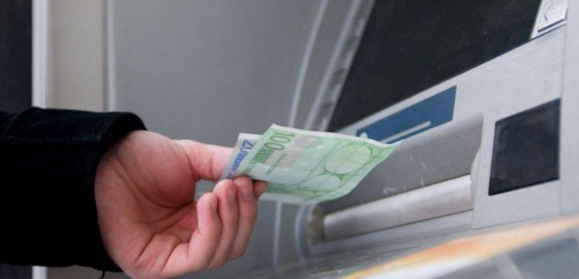 Un hombre sacando dinero en efectivo de un cajero, con todos sus billetes en una mano / EFE