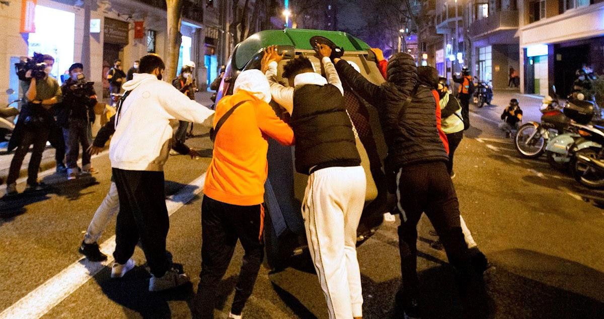 Un grupo de jóvenes mueve un conenedor para formar una barricada en la calle Villarroel / EFE