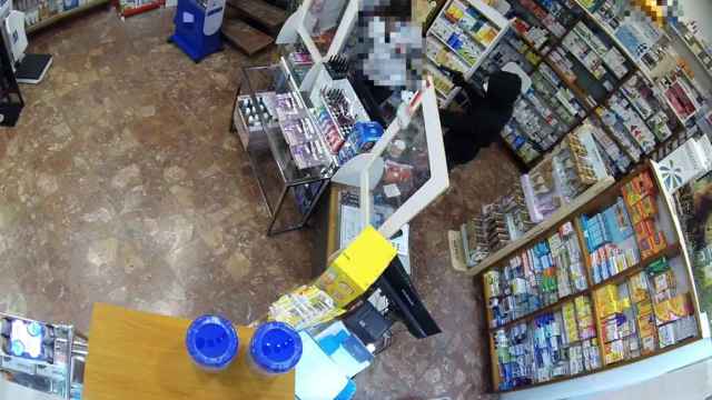 Uno de los atracadores apunta con una pistola a la empleada de una farmacia de Tarragona / MOSSOS