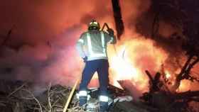 Un bombero durante las tareas de extinción del fuego en un asentamiento de barracas junto a la carretera de Terrassa / BOMBERS