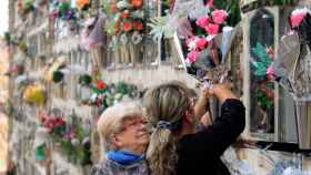 Dos usuarias dejan flores en la sepultura de un ser querido en un cementerio de Barcelona / CG