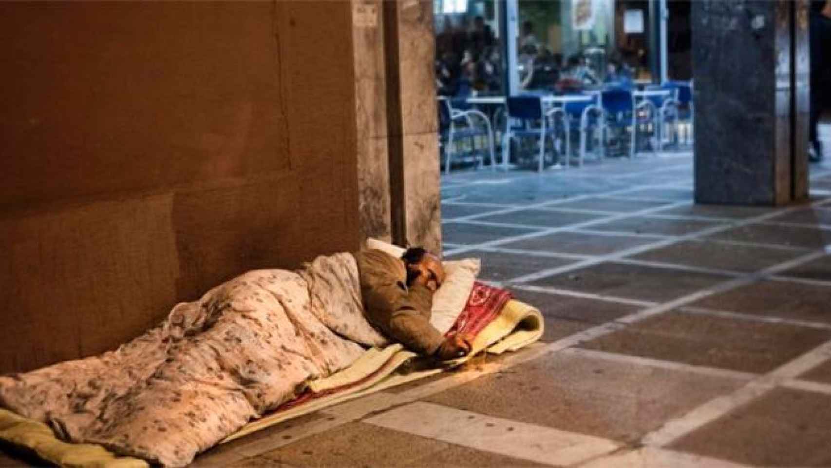 Un sintecho duerme en la plaza Real de Barcelona / CG