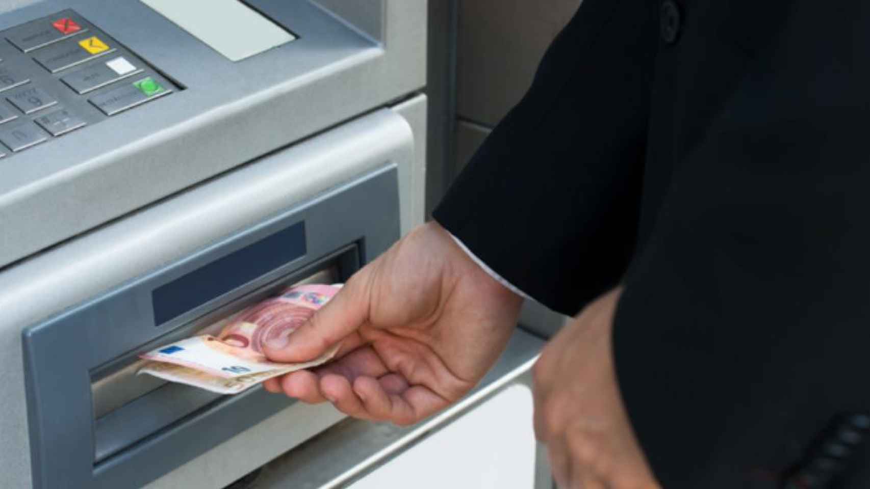 Un hombre retira efectivo de un cajero automático, en una sucursal bancaria pronta a su desaparición