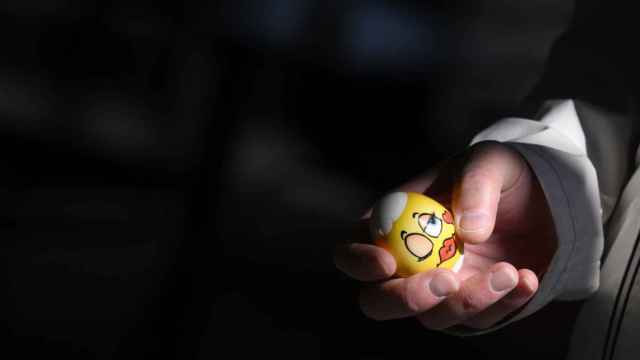 Un hombre sujeta un huevo de Pascua durante el tradicional combate de huevos de Pascua, este domingo en Berna / EFE