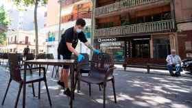 Imagen del propietario de un bar limpiando y preparando su terraza en Barcelona / EFE