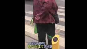 Una foto de una mujer mojándose con el chorro de agua por intentar pasar en rojo