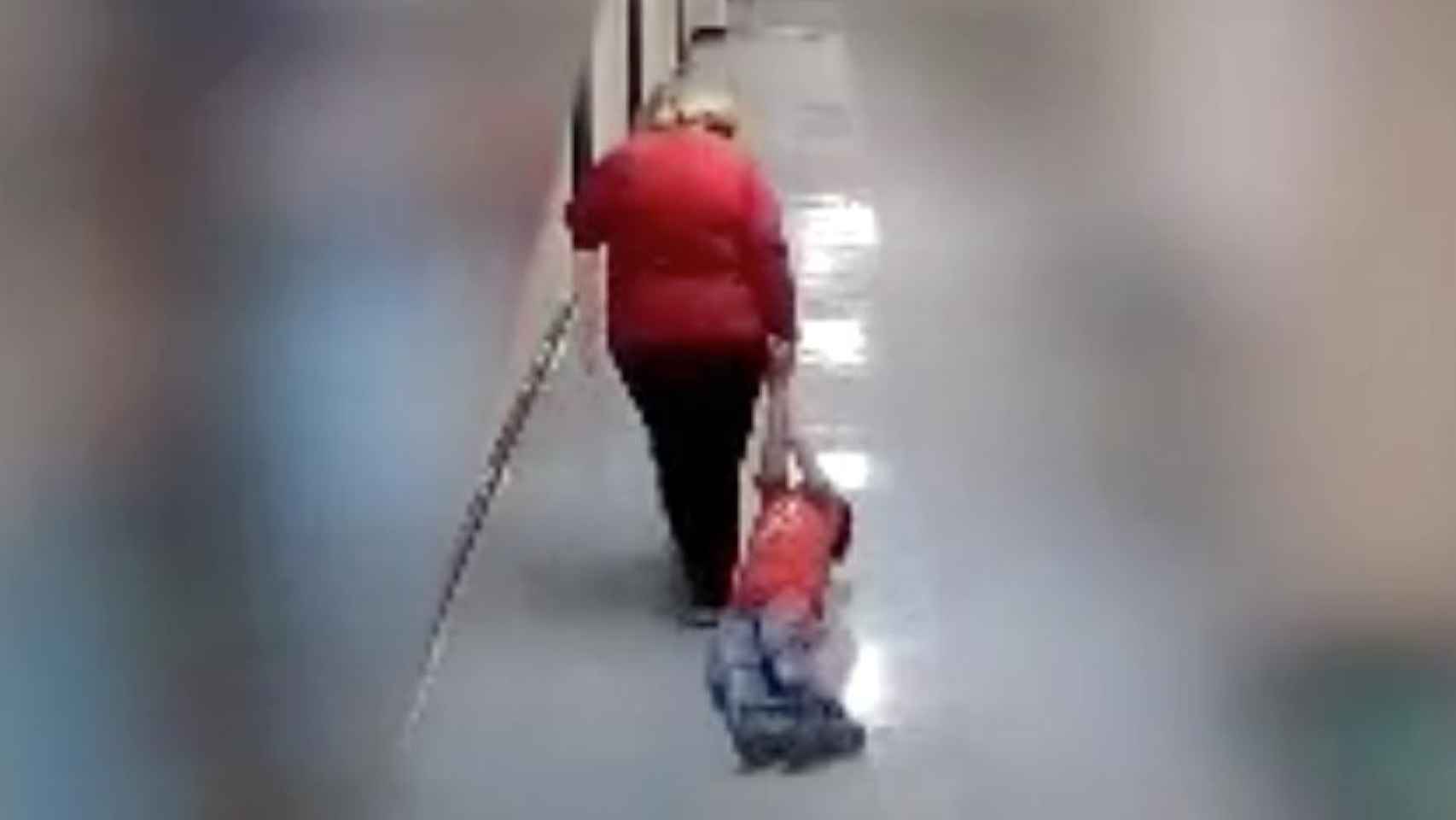 Una profesora arrastra por los suelos a un niño con autismo