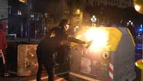 Un encapuchado quema un contenedor tras la manifestación contra las restricciones en Barcelona / PABLO MIRANZO (CRÓNICA GLOBAL)