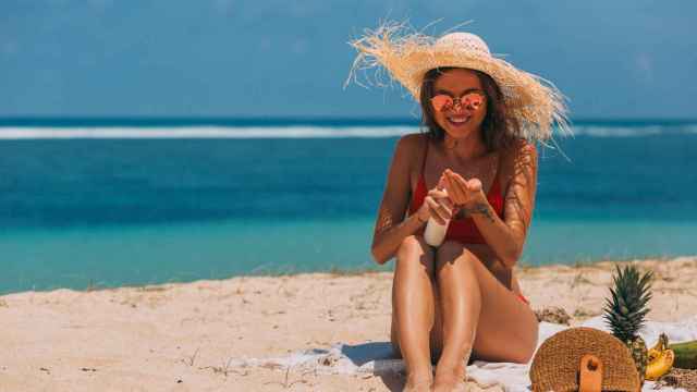 Una mujer se pone crema en la playa: los protectores solares son indispensables en verano / PEXELS