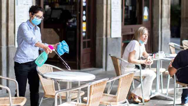 Imagen de una restauradora desinfectando una mesa en la Plaza Real de Barcelona / EFE