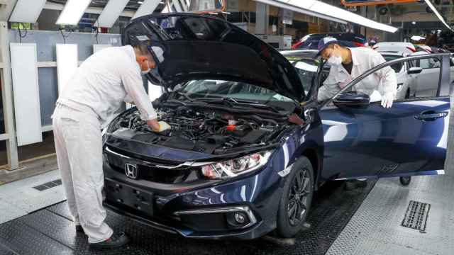 Dos hombres trabajan en una fábrica de automóviles con un vehículo Honda / EP