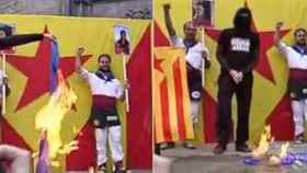 Encapuchados queman una bandera de la UE y otra de España durante la Diada de 2012, mientras dos jóvenes independentistas muestran las fotografías de dos etarras condenadas por terrorismo