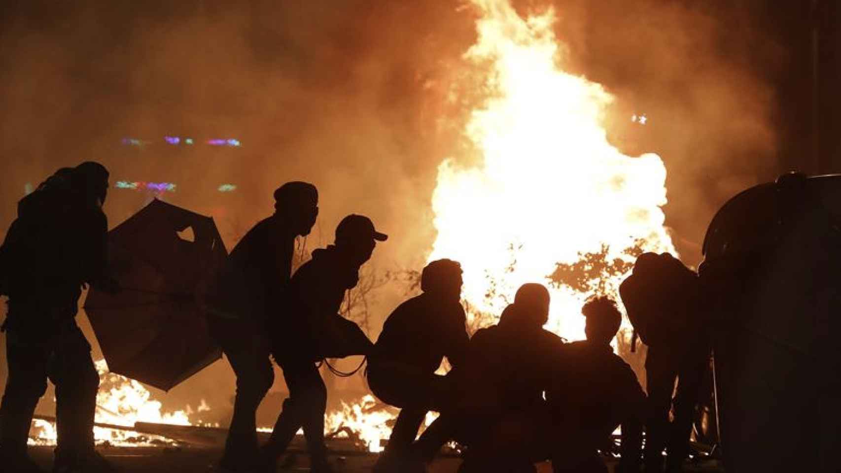 Manifestantes entre las llamas durante los altercados en Barcelona / EFE