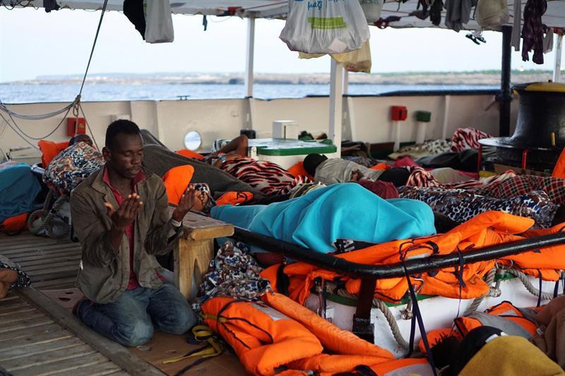 Un hombre reza en la cubierta del Open Arms, frente a la costa de Lampedusa / EFE