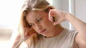 Una foto de archivo de una mujer con molestias en los oídos por el zumbido