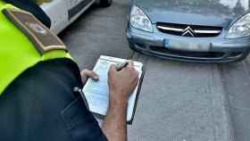 Un policía local pone una multa a un vehículo mal aparcado / CD