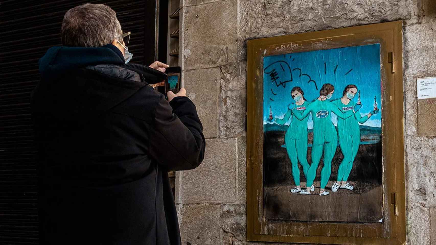 Un hombre fotografía la obra 'Las tres Vacunas', en Barcelona / MATHIAS ORESTELE - ZUMA WILE - DPA