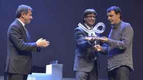 Óscar Camps (d) recibe el premio e Català de l'Any 2016 de manos de Carles Puigdemont en presencia de Agustí Cordón, primer ejecutivo del Grupo Zeta