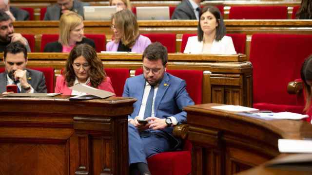 Pere Aragonès (d), presidente del Govern, consultando su móvil en el Parlament / EP