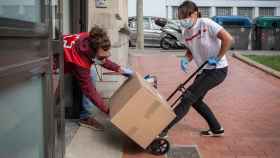 Varios voluntarios de Cruz Roja reparten cajas con alimentos y otros productos en Cataluña / EP